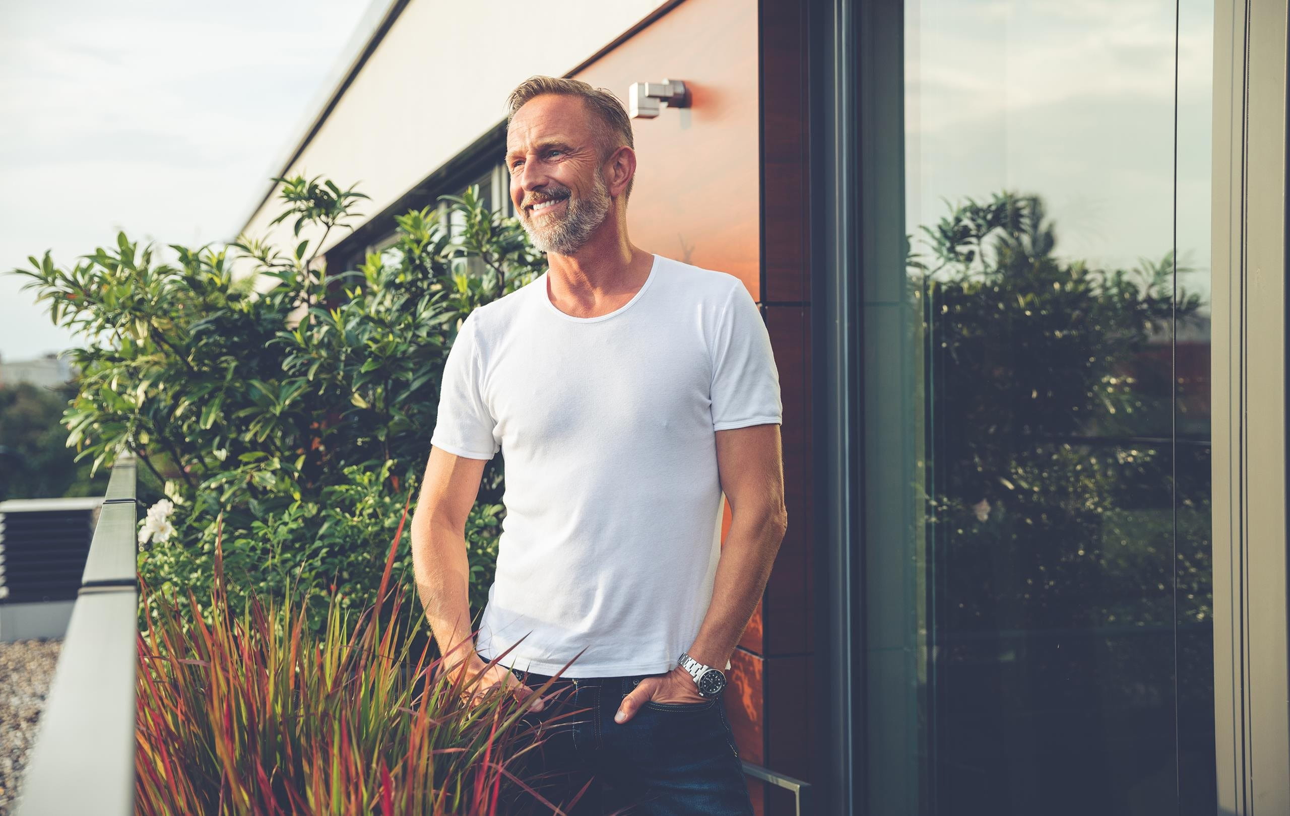 Man in white T-shirt smiling on the balcony