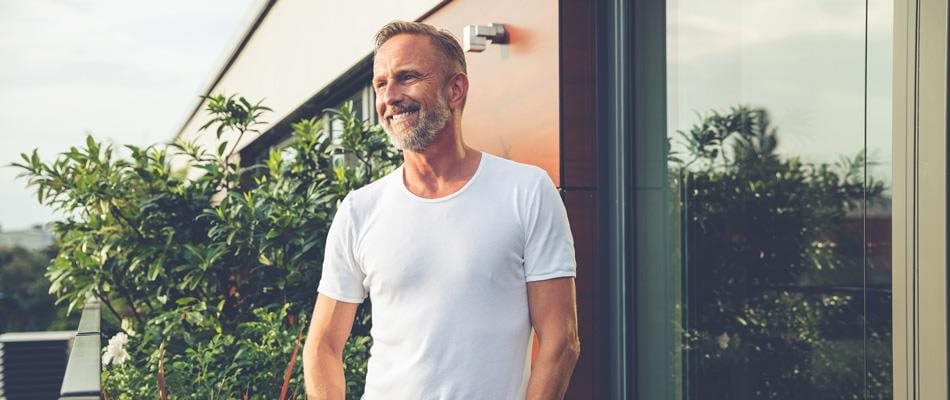 Homme en T-shirt blanc souriant sur le balcon