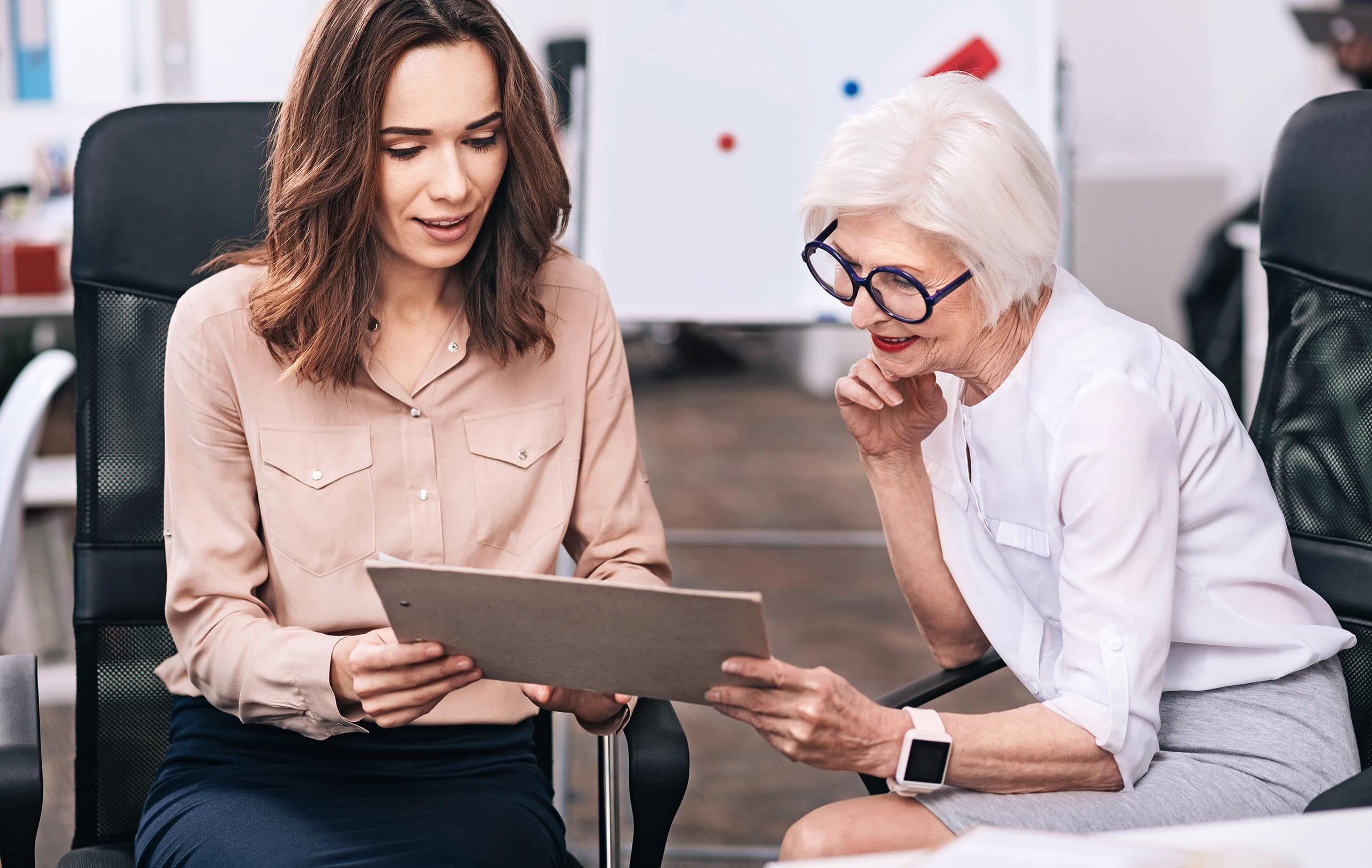 Una donna di affari giovane e una donna anziana discute il progetto Una donna di affari giovane e una donna anziana discute il progetto