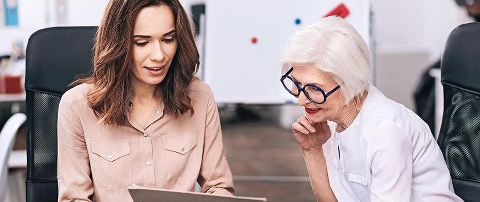 A younger and an older businesswoman discuss the project