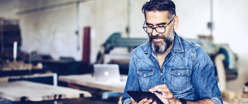 Mann sits in his workshop and analyzes various pension fund solutions on his tablet