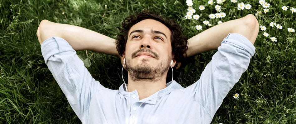 L'uomo giace sul prato, guarda il cielo e ascolta la musica.