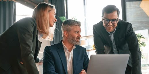 Drei Personen schauen in einen Laptop